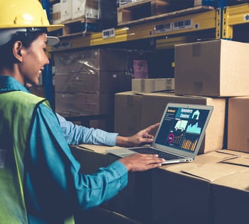 An employee using a laptop in a warehouse