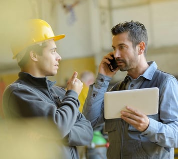 Two warehouse employees looking at an asset management dashboard and discussing the status of employee toolkits 