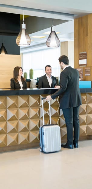 A new guest is welcomed by two hotel front desk staff