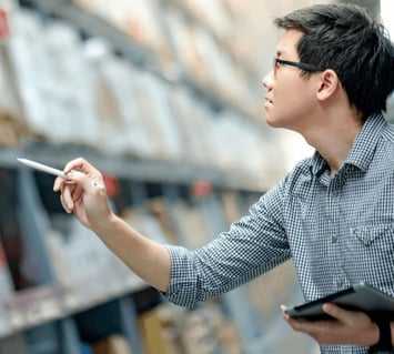 An employee manages warehouse inventory using a tablet