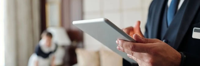 A hotel employee using a tablet to manage housekeeping operations