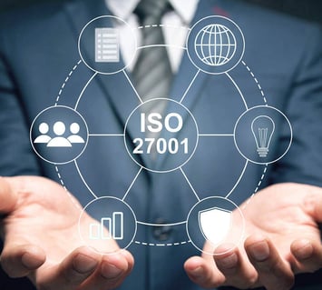 Close-up of a business professional holding ISO 27001 compliance icons, symbolizing the importance of certified information security systems.