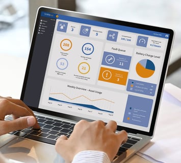 An employee uses a smart asset management system to track and analyze warehouse equipment and handheld scanners