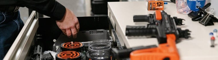 Law enforcement officer organizing less-lethal weapons and accessories in secure storage. Proper management of less-lethal weapons enhances security, accountability, and compliance.