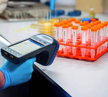 Scientist using RFID handheld scanner for laboratory asset tracking and compliance.