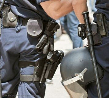 Close-up of law enforcement officers with holstered sidearms and batons, highlighting the need for secure weapon storage and accountability.