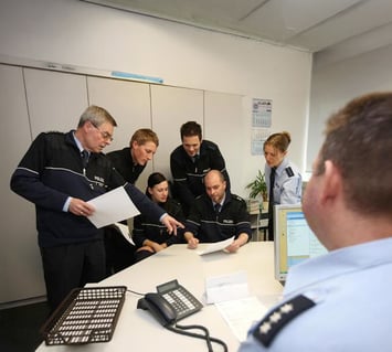 Law enforcement team gathered around a desk reviewing weapons management policies and procedures for improved accountability.