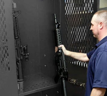 Police officer storing a firearm in a secure armory locker, demonstrating best practices in automated weapons tracking systems.