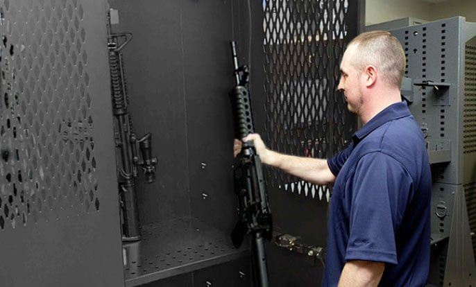 A law enforcement officer grabs a long gun from the police armory