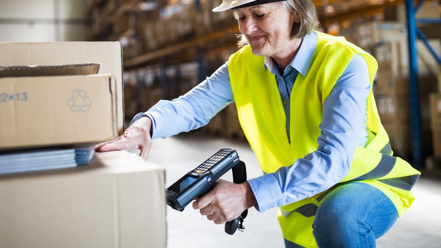 An employee using a hand held scanner to track and manage warehouse inventory